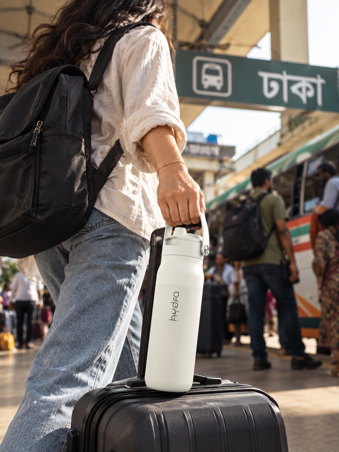 A traveller carrying a white Hydra by its handle at a Dhaka bus terminal.